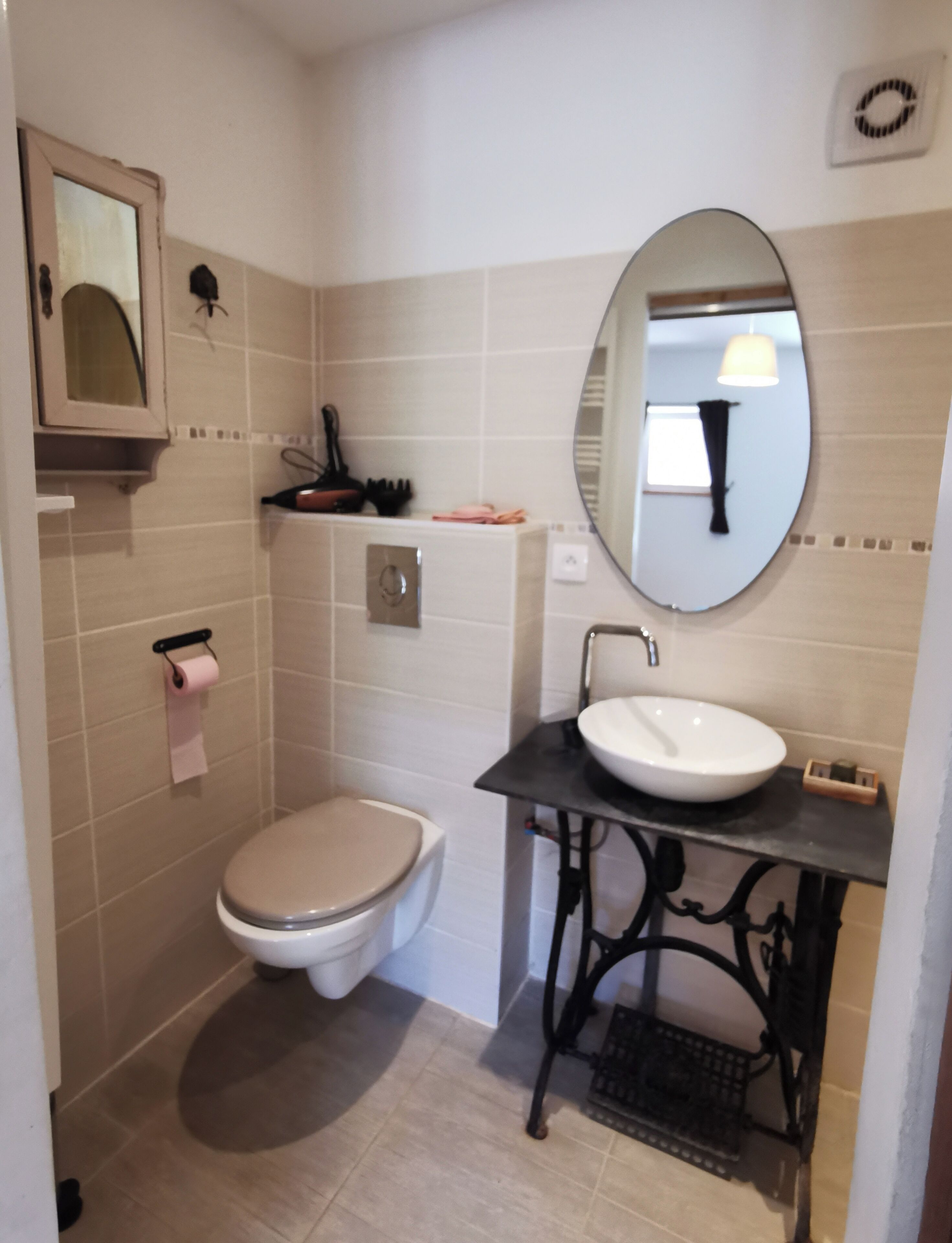 Une salle de bain équipée de toilettes, d’un lavabo, d’un miroir et d’un porte-serviettes.