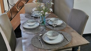 A dining table set with plates, glasses, and a vase of flowers. - La Cense du pont. Gîte in square farmhouse. Lille and Tournai campaign. (Bachy)