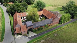 A rural property with a brick building, a small attached structure, and a paved driveway. - La Cense du pont. Gîte in square farmhouse. Lille and Tournai campaign. (Bachy)