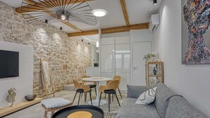 Ein modernes Wohnzimmer mit einer Steinwand, einem runden Tisch, einer Couch und einem an der Wand montierten Fernseher.