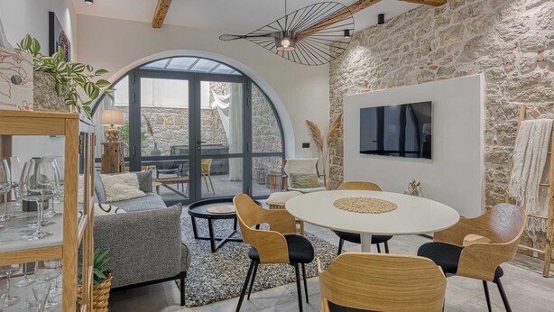 Ein modernes Interieur mit Steinwand, einem runden Esstisch und einem großen Bogenfenster.