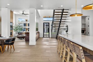 A modern kitchen with a central island, wooden flooring, and a staircase leading to a loft area. - Spacious 7 Bed Private Pool + Pickleball (Hurricane)