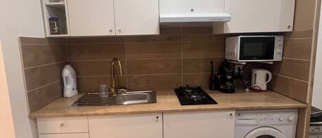 A compact kitchen with a sink, microwave, and washing machine.