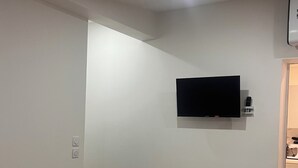 Une pièce dotée d’un téléviseur fixé au mur, d’un plancher en bois et d’un éclairage encastré au plafond.
