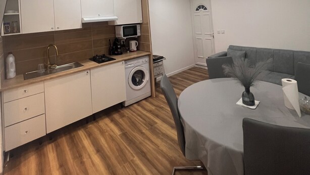 Une cuisine compacte équipée d’un lave-linge, d’un four à micro-ondes et d’une machine à café.