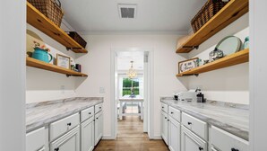 A kitchen with white cabinets, wooden shelves, and a marble countertop. - Farm Stay in Hot Springs | Hot Tub • Museum • Pet Friendly (Hot Springs)