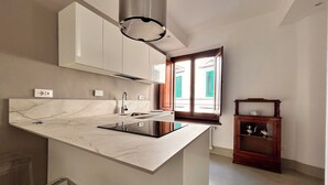 Een moderne keuken met een marmeren aanrecht, een roestvrijstalen spoelbak en een ingebouwde kookplaat.