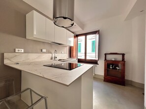 A modern kitchen with a marble countertop, stainless steel sink, and a built-in stove. - Casa Aligi by FlorenceHospitality (Firenze)