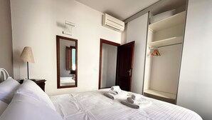 Een hotelkamer met een bed, een spiegel, een airconditioning en een kledingkast.
