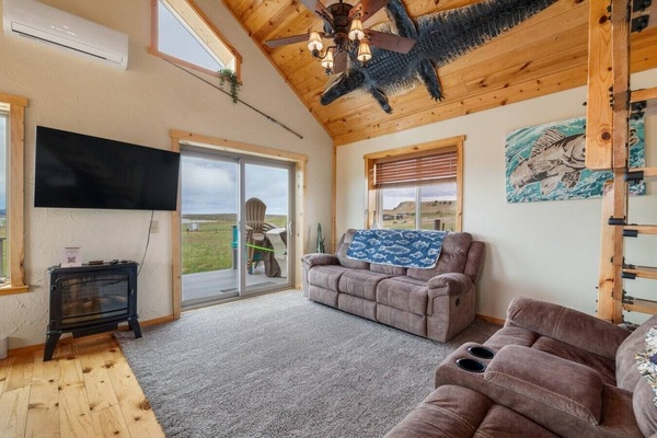 Unwind in a cozy lounge featuring plush seating, a warm fireplace, and expansive windows showcasing scenic hill views.