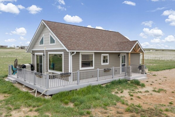 A single-story house with a covered porch, large windows, and a fenced deck area.