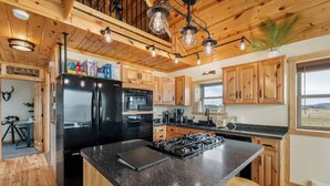 Une cuisine avec des meubles de rangement en bois, un réfrigérateur noir, une cuisinière et un panneau indiquant le mot « LAC ».