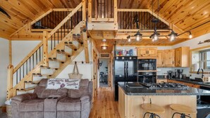Un intérieur en bois comprenant un canapé, une cuisine et un escalier.