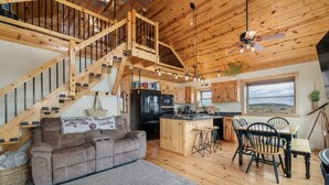 Un vaste espace de vie agrémenté d’un escalier en bois, une cuisine dotée d’un grand îlot central et un coin repas offrant une vue agréable.