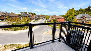 Ein Balkon mit Blick auf eine Vorstadtstraße, Häuser und eine Straße.