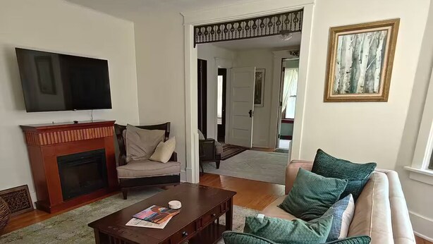 Ein Wohnzimmer mit Kamin, Sofa, Couchtisch und Fernseher.