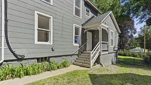 A two-story house with a front porch, a staircase, and a small garden area. - Near EMU & Ann Arbor | King Bed, AC & WiFi (Ypsilanti)