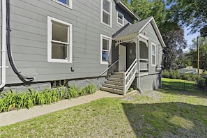 A two-story house with a front porch, a staircase, and a small garden area.