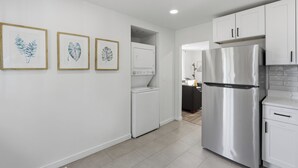 A modern kitchen with white cabinets, a stainless steel refrigerator, and a washing machine. - Near EMU & Ann Arbor | King Bed, AC & WiFi (Ypsilanti)