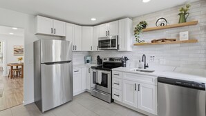 A modern kitchen with stainless steel appliances, white cabinetry, and a built-in oven. - Near EMU & Ann Arbor | King Bed, AC & WiFi (Ypsilanti)