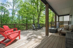 A wooden deck with Adirondack chairs, a sofa, and a grill. - 3BR Retreat w/ Deck + Fire Pit | Sleeps 8 | Free Tix (Hendersonville)
