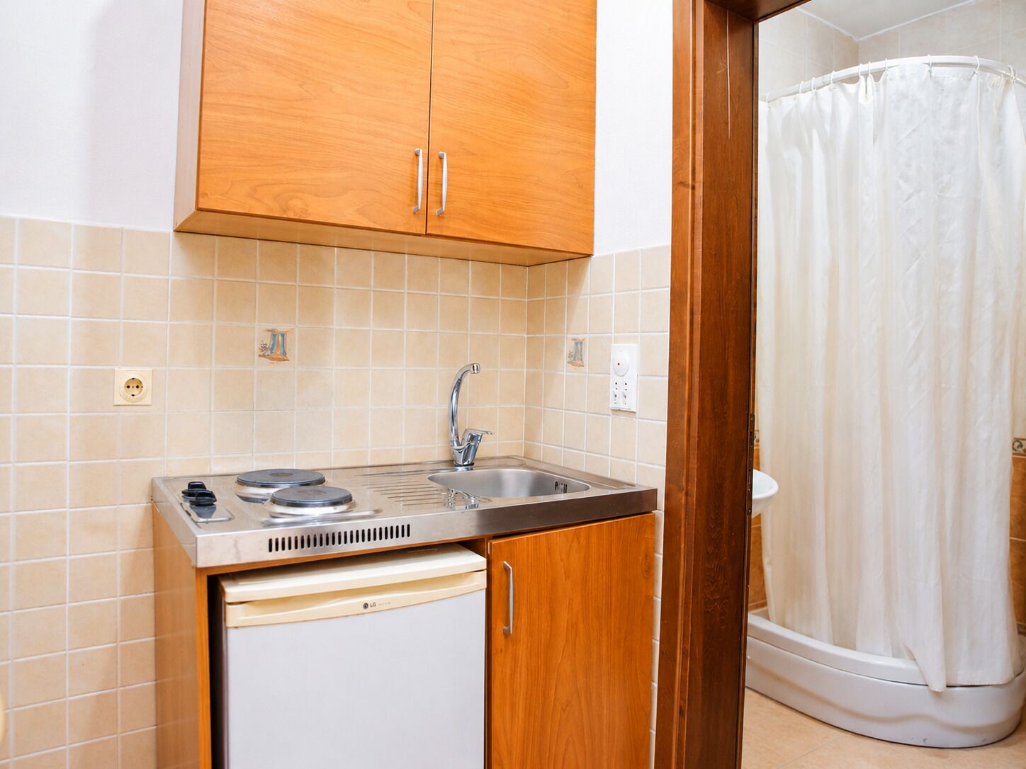 A compact kitchen with a sink, a dishwasher, and wooden cabinets.
