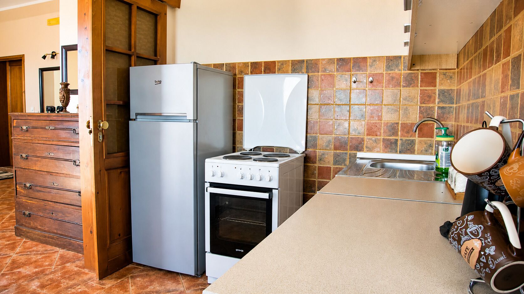 A compact kitchen with a refrigerator, oven, and a stove.