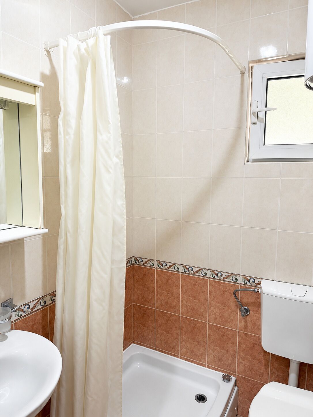 Un bagno con tenda doccia, lavandino, vasca e WC.