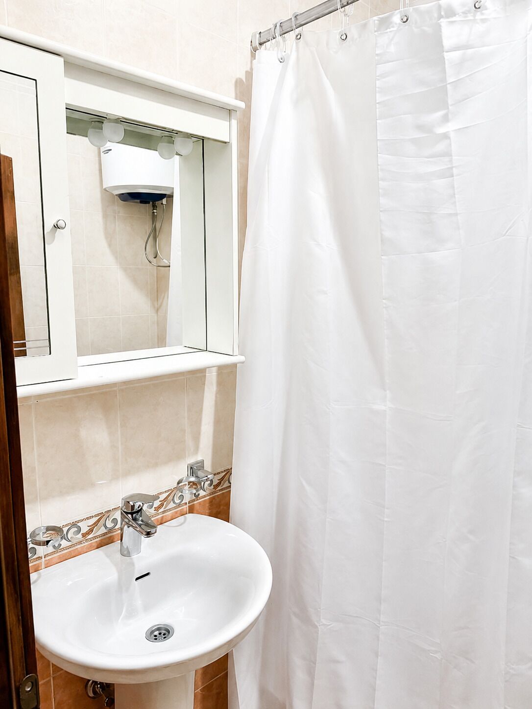 Ein Badezimmer mit einem weißen Waschbecken, einem Spiegel und einer Duschvorhang.