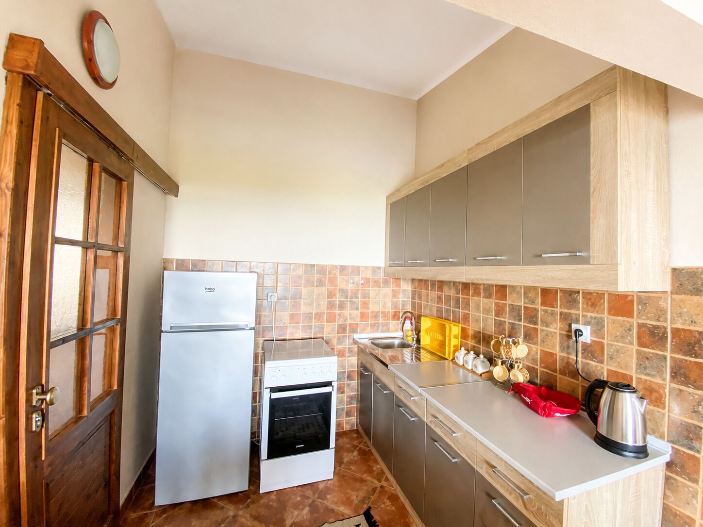 Una cucina compatta con frigorifero, forno e lavello.