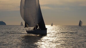 Un velero en aguas tranquilas con una costa lejana.