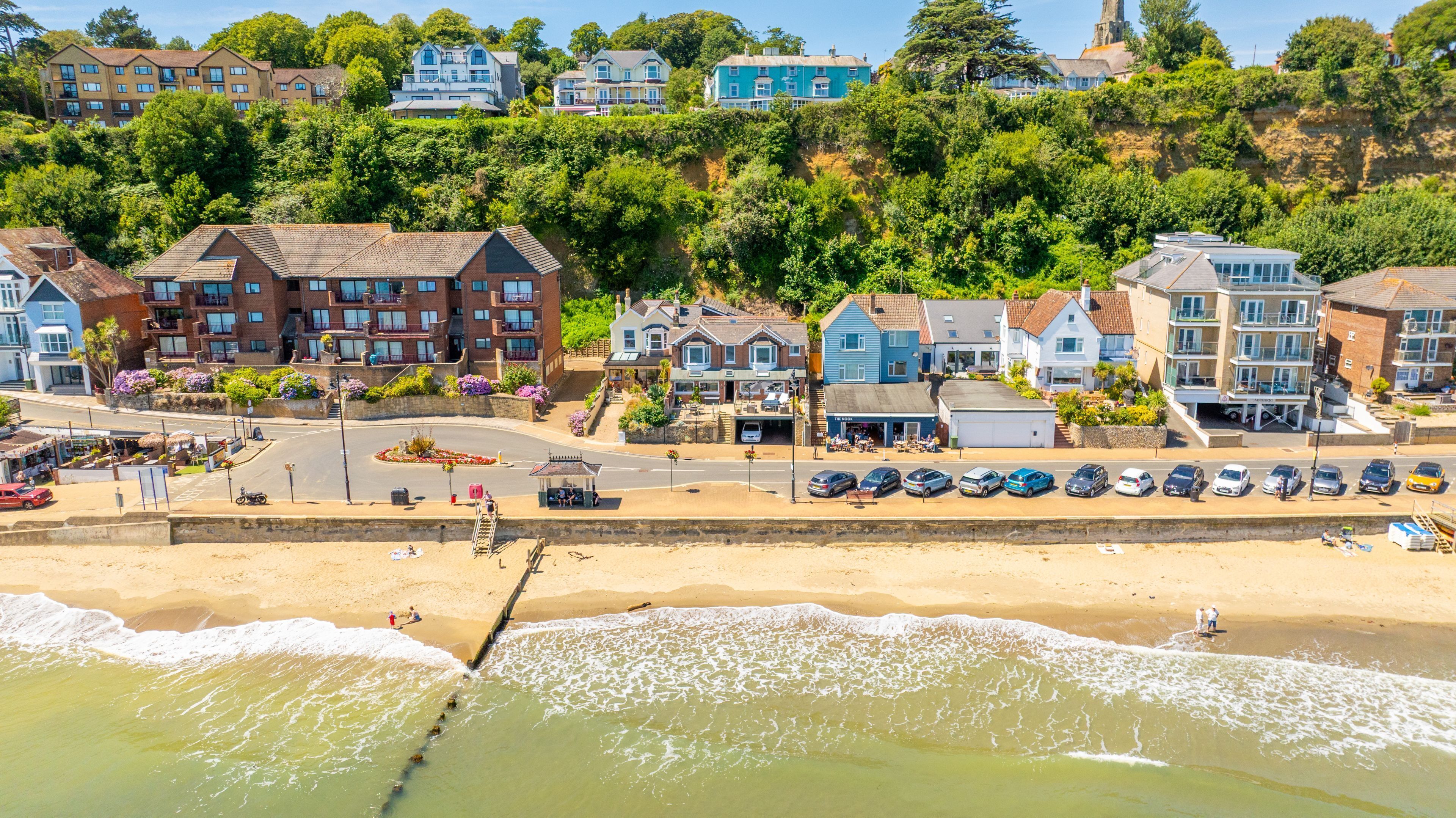 A coastal town with beachfront properties, a sandy beach, and a pier.