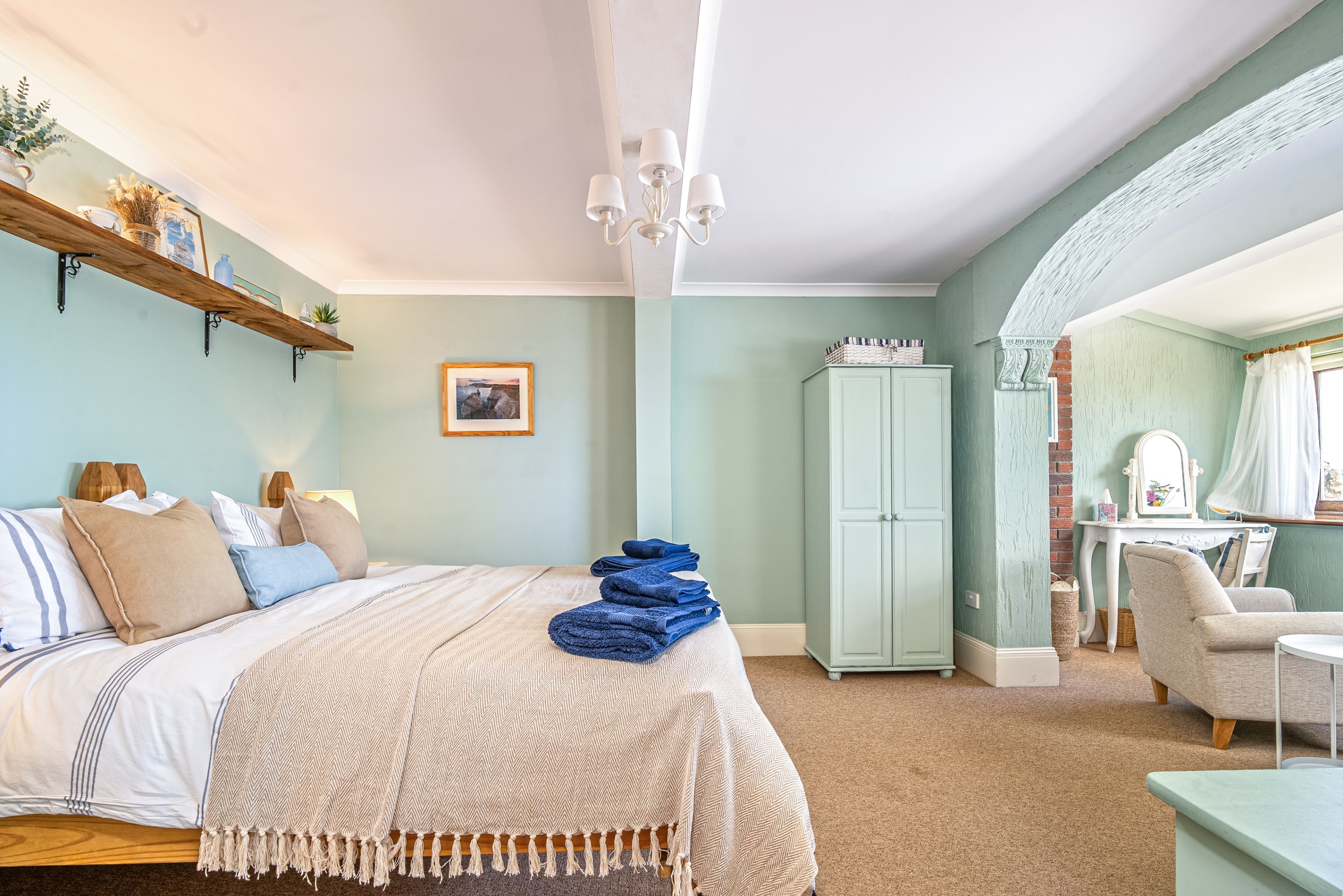 Een slaapkamer met een bed, een kaptafel, een dressoir en een stoel.