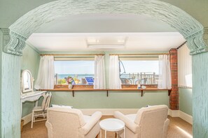 A room with a view of the sea, featuring two chairs, a small table, and a window with curtains. - Shanklin Beach House -  an apartment that sleeps 7 guests  in 3 bedrooms (Shanklin)