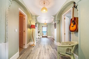 A hallway with a wooden floor, a hanging guitar, a wicker chair, and a lamp. - Shanklin Beach House -  an apartment that sleeps 7 guests  in 3 bedrooms (Shanklin)