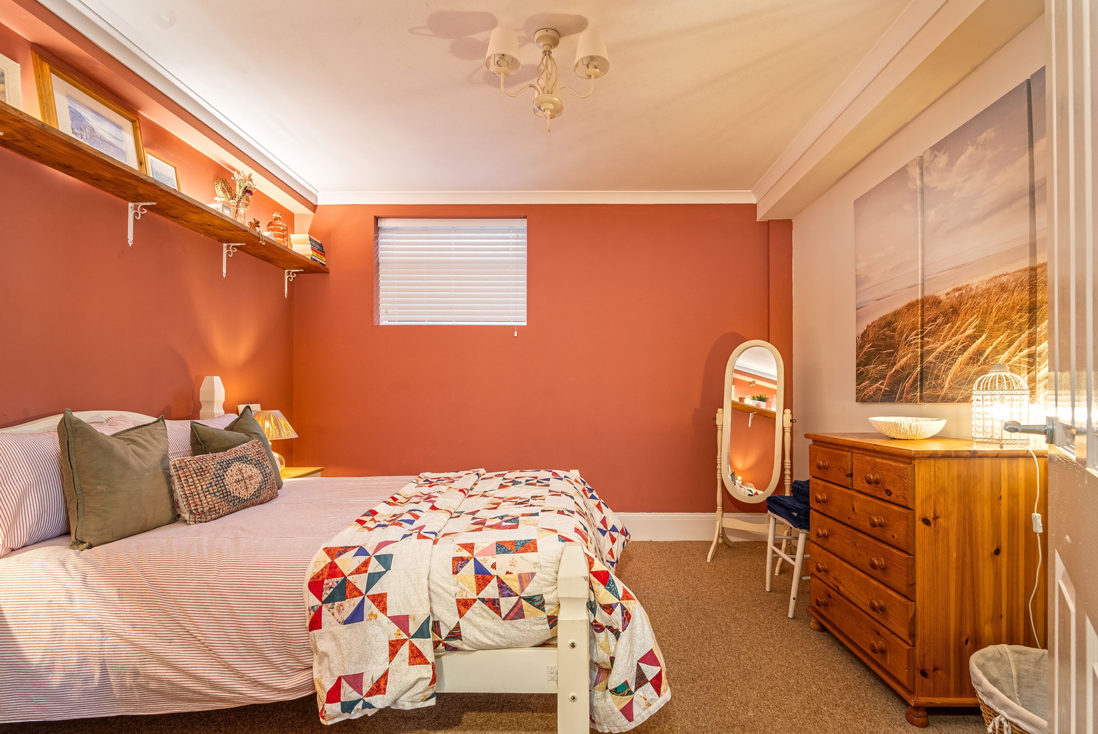 Un dormitorio con cama, cómoda, espejo y ventana con persianas.