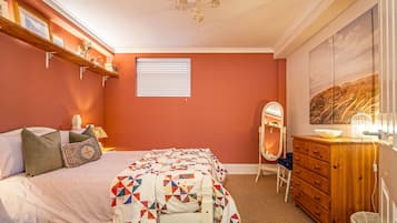 Un dormitorio con cama, cómoda, espejo y ventana con persianas.