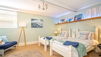 Une chambre avec deux lits, une table de chevet, une lampe, une chaise, un tapis et des œuvres d’art accrochées aux murs.