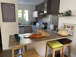 A modern kitchen with a wooden countertop, a sink, a stove, and a dining area with stools. - La Marana house, beach 100m away, air-conditioned, terrace and garden. Sleeps 4/6. (Borgo)
