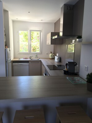 A modern kitchen with a dishwasher, a coffee machine, and a window with a view of greenery. - La Marana house, beach 100m away, air-conditioned, terrace and garden. Sleeps 4/6. (Borgo)
