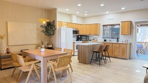 A modern kitchen with wooden cabinets, a dining area with a table and chairs, and a small island with stools. - 4-bedroom house in Sedona with hot tub, firepit & grill - walk to hiking trails (Sedona)