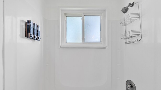 Ein Badezimmer mit Badewanne, Fenster, Handtuchhalter und einer Reihe von Pflegeprodukten.
