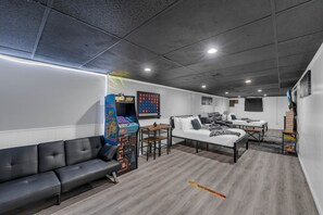 Un área de estar moderna con un sofá, una mesa de juegos y un televisor montado en la pared.