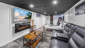 Ein modernes Wohnzimmer mit Kamin, großem Fernseher, einer Couch und einem Bett.