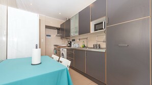 A modern kitchen with grey cabinets, a microwave, a stove, and a sink.