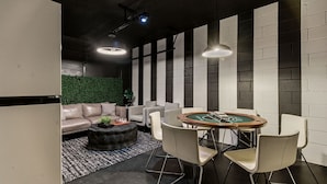 Un área de lounge moderna con mesa de billar, sofás y una pared verde.