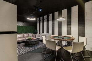 Ein stilvoller Lounge-Bereich mit Billardtisch, Sofas und einer grünen Wand.