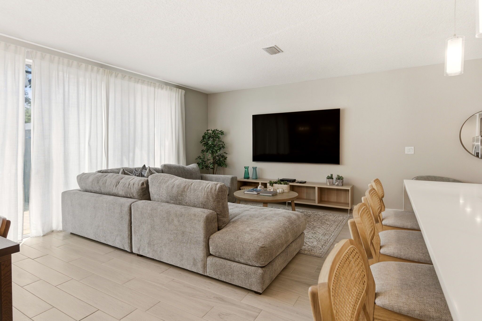 A modern living room with a sofa, a coffee table, and a TV mounted on the wall.