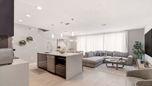 Una cocina moderna con isla integrada, un sofá gris y una mesa de centro en una sala de estar.