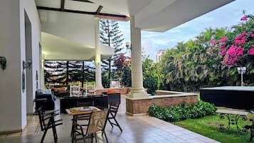 Une terrasse extérieure avec une table et des chaises, entourée de verdure et agrémentée d’une fontaine.